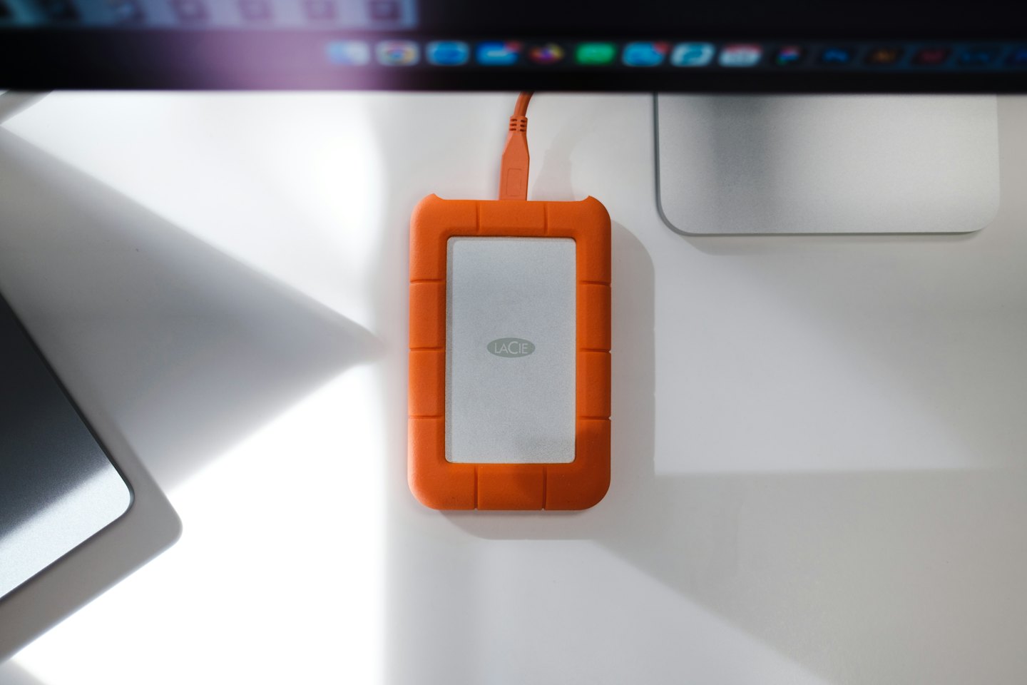 Orange external hard drive connected to a computer on a desk.