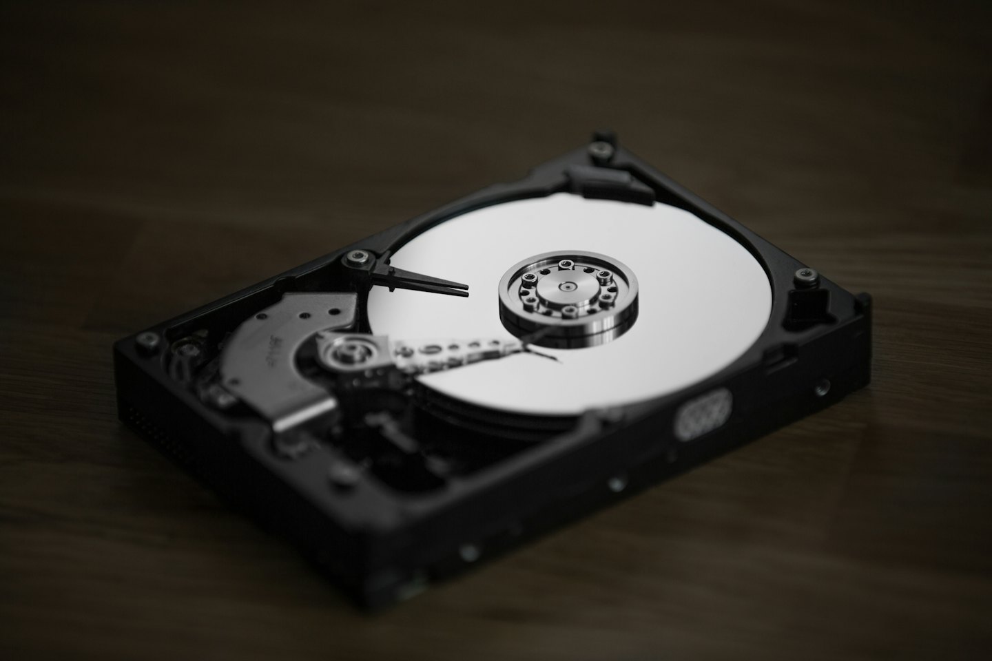 Opened computer hard drive showing internal components on a desk.