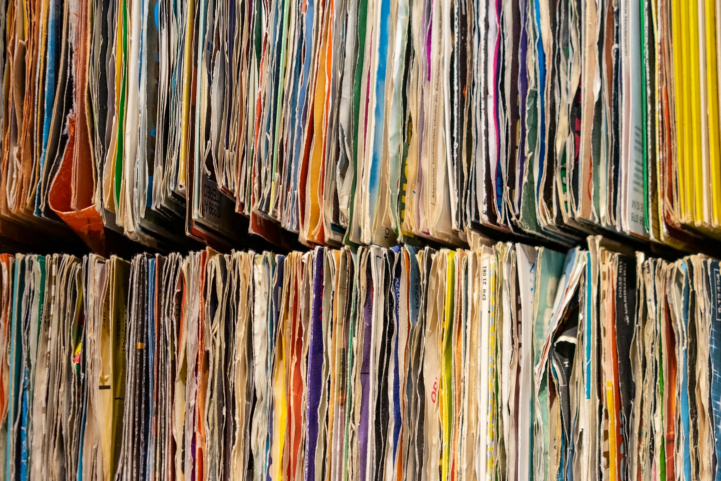 Vintage vinyl record albums stacked vertically on two shelves.